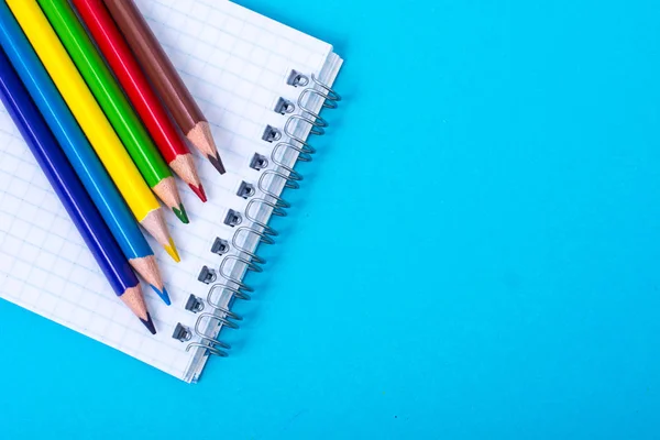 Blocco note e matite colorate su sfondo colorato — Foto Stock