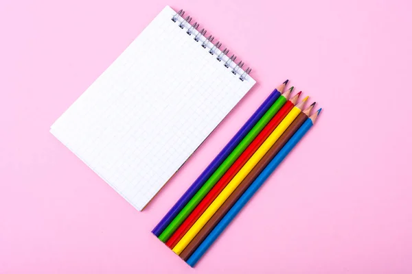 Blocco note e matite colorate su sfondo colorato — Foto Stock