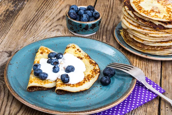 Amerikanische Pfannkuchen mit Sauce und Blaubeeren auf hölzerner Tischplatte — Stockfoto