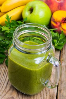 Cam ahşap arka plan üzerinde taze karıştırılmış yeşil smoothie