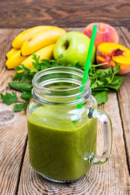 Cam ahşap arka plan üzerinde taze karıştırılmış yeşil smoothie