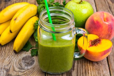 Cam ahşap arka plan üzerinde taze karıştırılmış yeşil smoothie