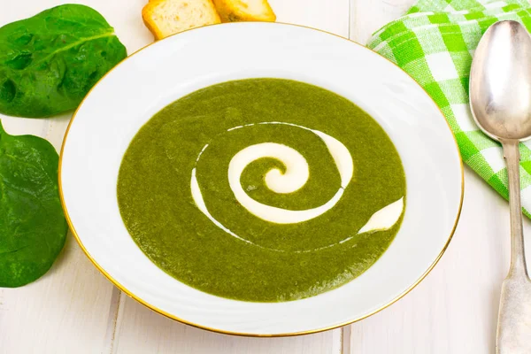 Beyaz ahşap masa üzerinde yeşil krem ıspanak çorbası