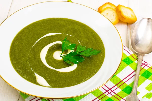 Beyaz ahşap masa üzerinde yeşil krem ıspanak çorbası