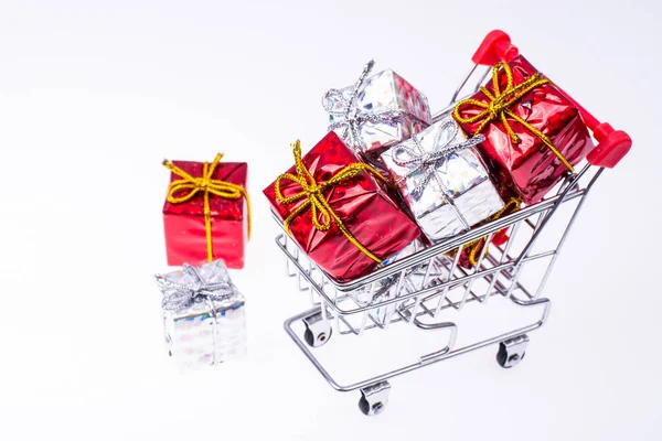 Einkaufswagen mit Weihnachtsgeschenken auf weißem Hintergrund — Stockfoto