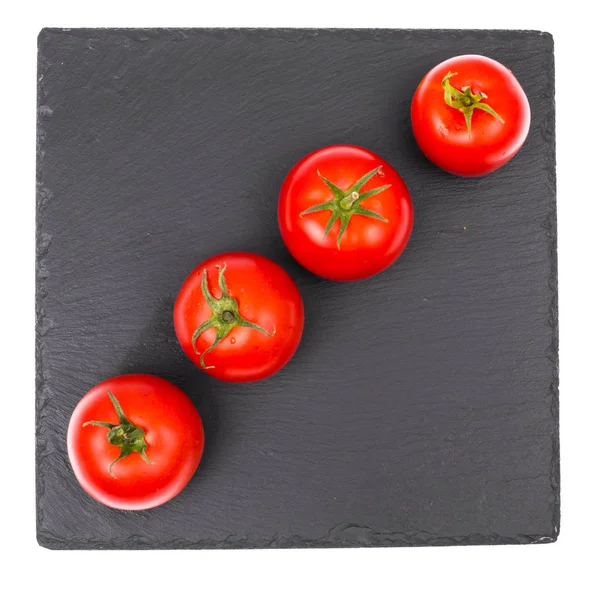 Tomates rojos maduros en plato de piedra negra — Foto de Stock