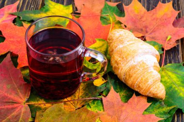 Kırmızı çay ile pembe ahşap masaya sonbahar yaprakları