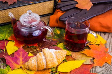 Aromatik kırmızı çay, kitap, ahşap masa üzerinde renkli sonbahar yaprakları