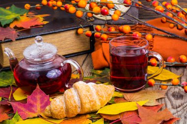 Aromatik kırmızı çay, kitap, ahşap masa üzerinde renkli sonbahar yaprakları