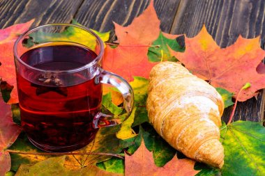 Kırmızı çay ile pembe ahşap masaya sonbahar yaprakları