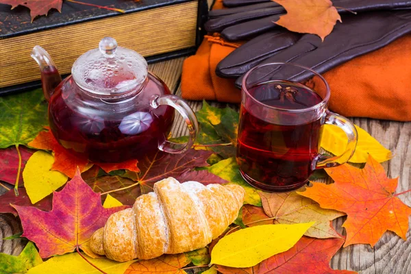 Aromatik kırmızı çay, kitap, ahşap masa üzerinde renkli sonbahar yaprakları