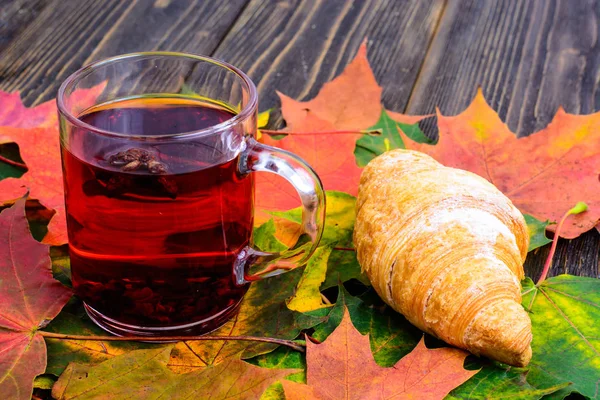 Kırmızı çay ile pembe ahşap masaya sonbahar yaprakları