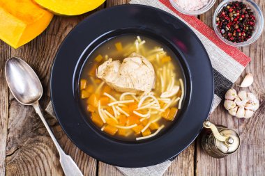 Tavuk, kabak ve ahşap masa üzerinde erişte çorbası