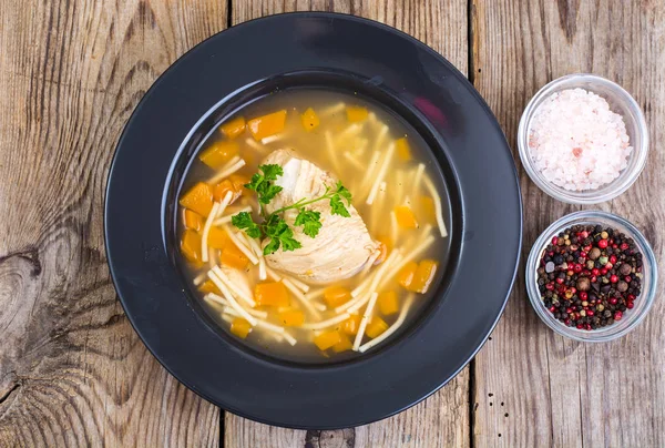 Sup dengan ayam, labu dan mie di atas meja kayu — Stok Foto