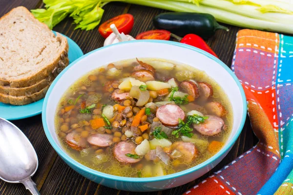 Soep met linzen, selderij en worstjes op oude houten tafel — Stockfoto