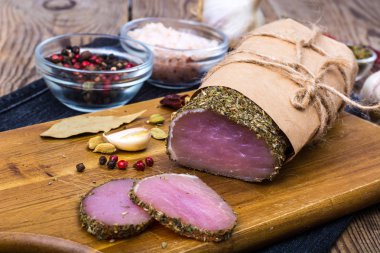 Sarımsak ve baharat ahşap arka plan üzerinde jambon füme parçası. Rustik tarzı