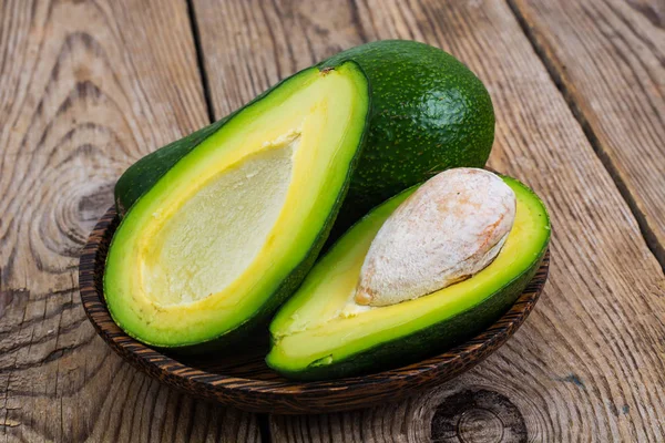 Taze bütün avokado ve yarım ahşap tablo