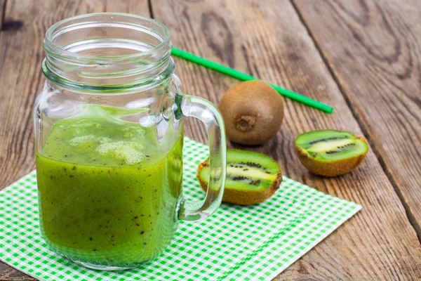 Grön god smoothie i glasburk och färsk kiwi på träbord — Stockfoto