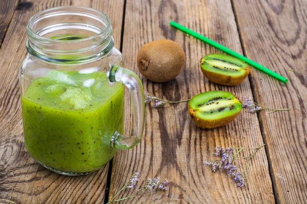 Grön god smoothie i glasburk och färsk kiwi på träbord — Stockfoto
