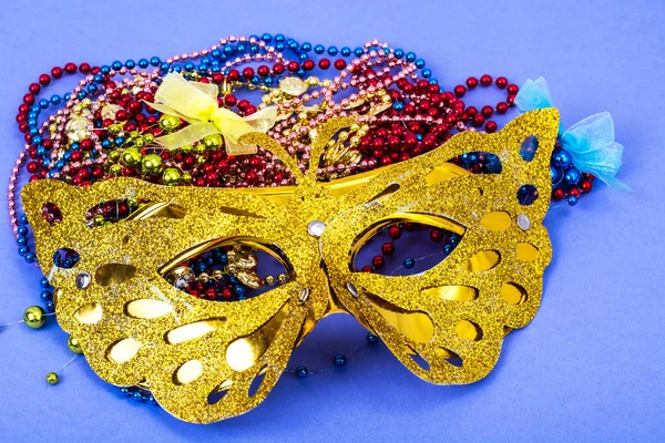 Gold carnival mask with colored beads on violet background — Stock Photo, Image