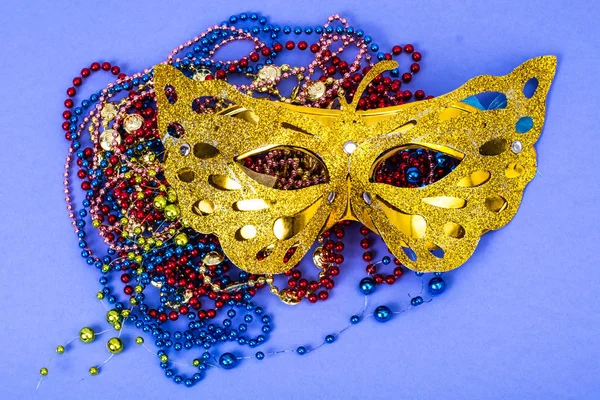 Masca de carnaval de aur cu margele colorate pe fundal violet — Fotografie, imagine de stoc
