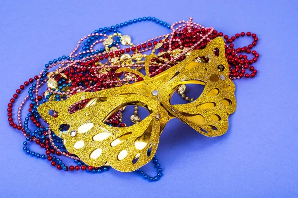 Gold carnival mask with colored beads on violet background — Stock Photo, Image