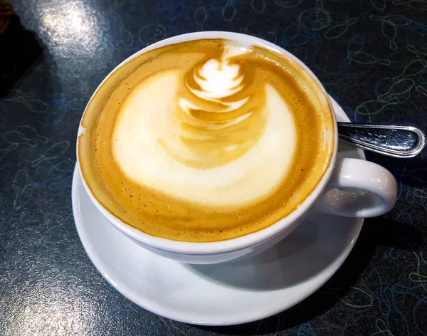 Cappuccino mit Zimt in weißer Tasse auf schwarzem Tisch — Stockfoto