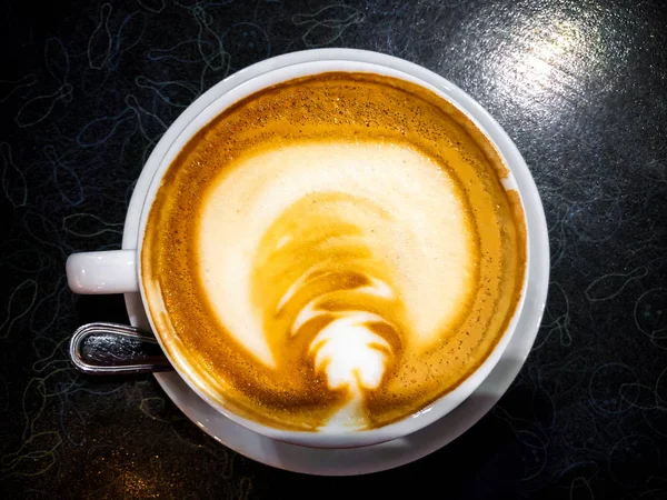 Cappuccino mit Zimt in weißer Tasse auf schwarzem Tisch — Stockfoto