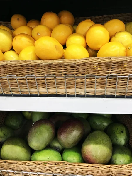 Zitronen und grüne Mango in Weidenkörben im Supermarkt — Stockfoto