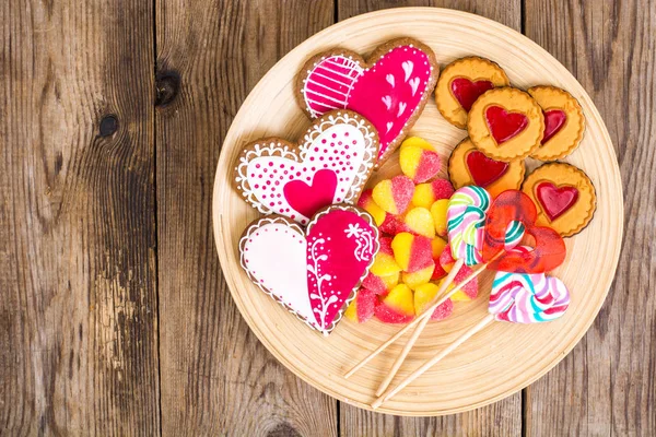 Zestaw słodyczy w kształcie serca na tabliczce na podłoże drewniane — Zdjęcie stockowe