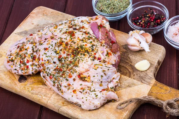 Turkey meat with spices and herbs on cutting board