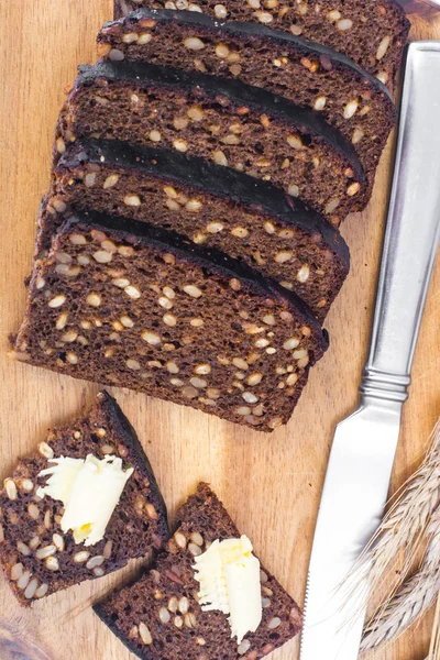 Pão de centeio fatiado com sementes de girassol e manteiga — Fotografia de Stock