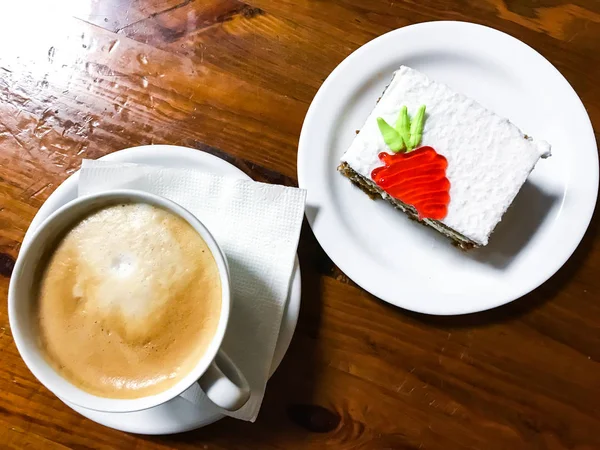 Piece of carrot cake and cappuccino on wooden table