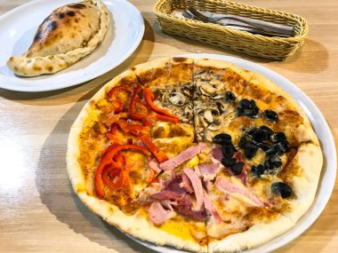 Ahşap masa üzerinde farklı dolguları ile pizza