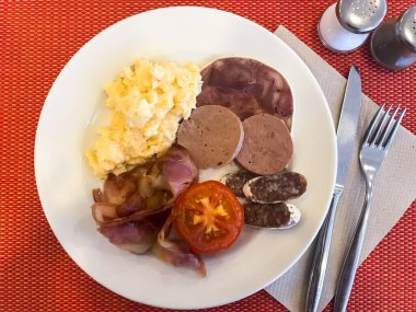 Tabakları kahvaltı masasına koyun. Çırpılmış yumurta, omlet, börek, kruvasan, şampiyon, kıtır pastırma, sosis. Üst görünüm 