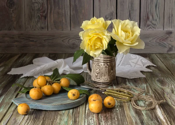 Плоды медлара и желтых роз — стоковое фото