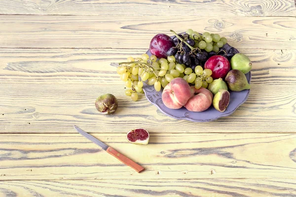 Летние фрукты в тарелке на столе — стоковое фото