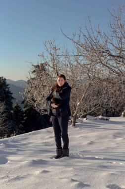 Genç, güzel bir kız Dağları ve ağaçları, arka planı günbatımında anlamına gelir ve bir kedi onun elinde tutan.