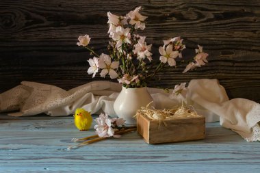 The easter composition. Eggs, a bouquet of almond branches and church candles on a wooden table close-up.   clipart