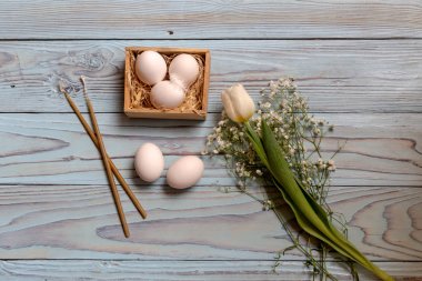 Paskalya kompozisyonu. Yumurta, beyaz lale ve ahşap masa yakın çekim kilise mumları.  