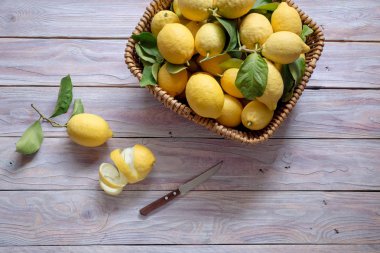 Ahşap masa yakın çekim üzerinde dokuma sepet içinde taze, olgun, toplanan limon.