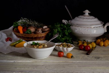 Taze, mantar çorbası-püresi bir kase, servis, kızarmış ekmek parçaları ve bir hasır sepet bir ahşap masa yakın çekim üzerinde sebze