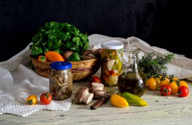 Sağlıklı beslenme. Marine sebze ve mantar kavanoz ve çiğ domates, biber, maydanoz ve ahşap masa yakın çekim üzerinde bir sepet içinde mantar.