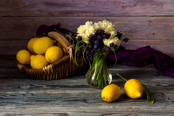 Wilde bloemen in een vaas en citroenen — Stockfoto