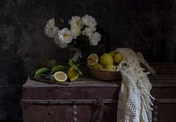 Bodegón con rosas en una caja vieja y limones de cerca . — Foto de Stock