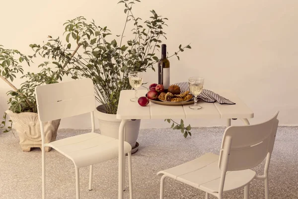 Table with peaches, bakery products and wine on the patio close-