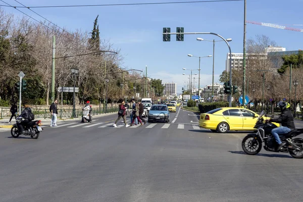 02 / 26 / 220. Atina şehri, Yunanistan. Vasileos Constantinou Bulvarı 'nın modern manzarası, arabalar, motosikletler ve şehir merkezinde güneşli bir kış sabahı insanlar.