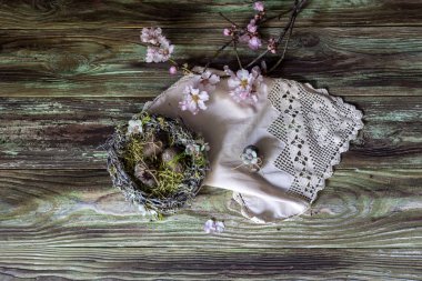 Paskalya kompozisyonu. Badem dallı bir buket, ahşap masa üzerinde eski usul yuva ve yumurtalar..