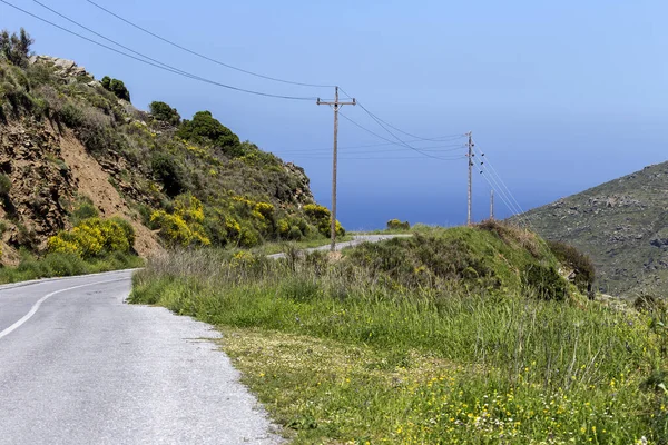 Güneşli bir bahar gününde denize bakan dar dağ yolu yılanı (Andros Adası, Kiklad, Yunanistan)