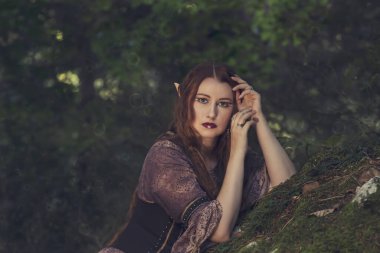 Cadılar Bayramı, karnaval ve tatil konsepti. Güzel cadılar bayramı genç elf kadın portresi. Ormanın derinliklerindeki güzel cadı kadın. Moda sanatı tasarımı. Cadılar Bayramı makyajlı seksi model kız..